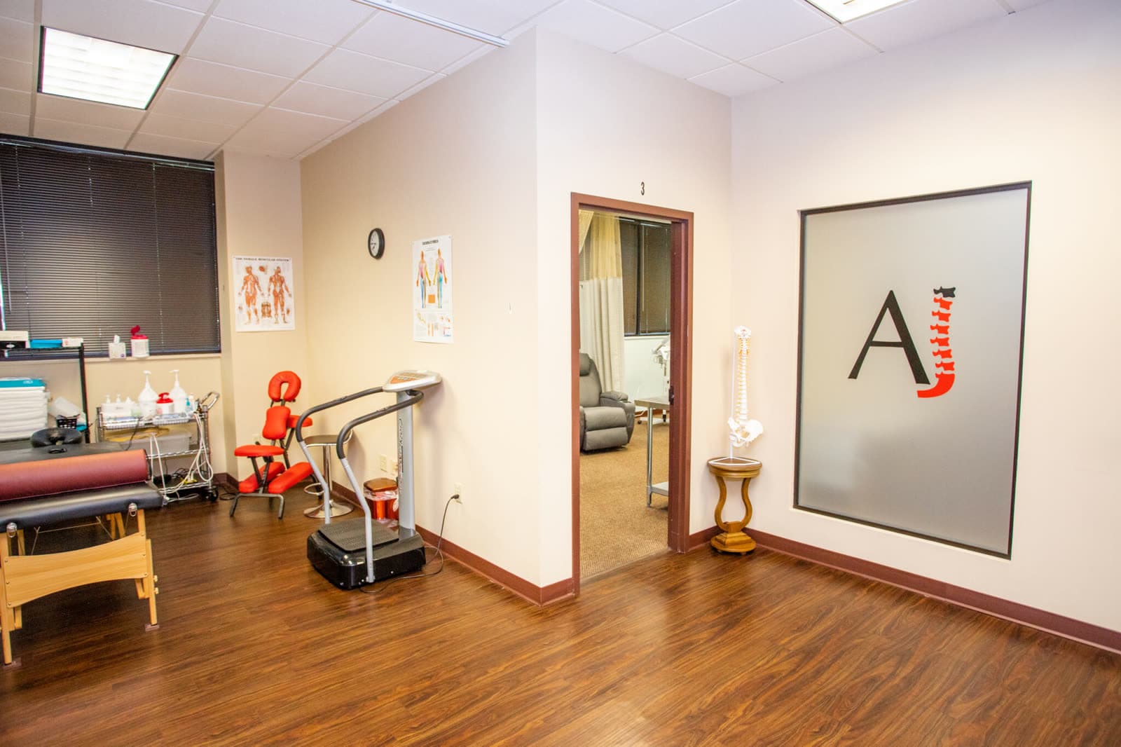 A treatment room at AJ Therapy Center with therapy tables and anatomical charts